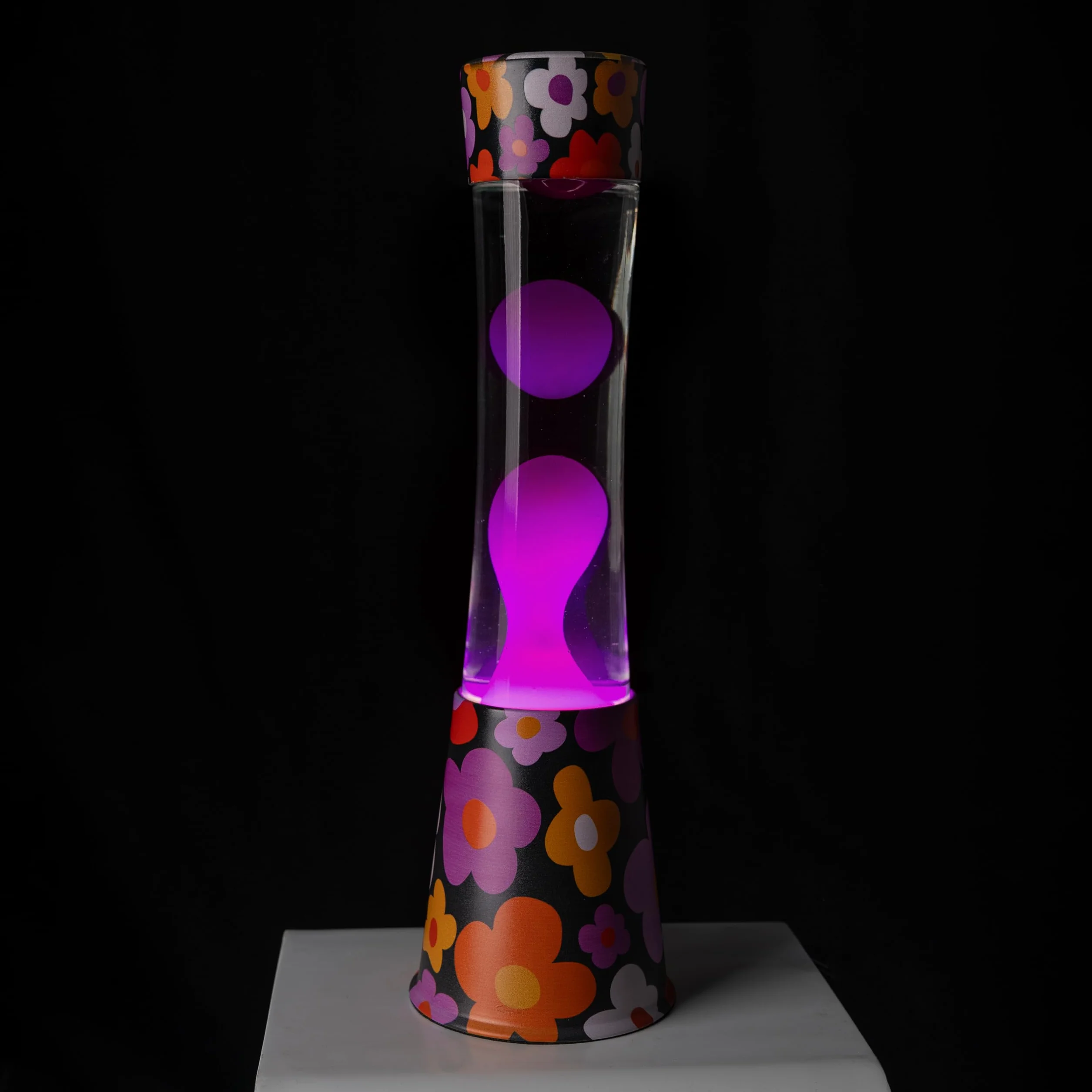 Fisura - Lámpara de lava “flores”. Base con estampado de flores, líquido transparente y lava rosa. Lámpara efecto relajante. Con bombilla de repuesto. 11 cm x 11cm x 39,5 cm.